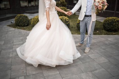 Gelin ve damat düğün günlerinde. Sevgi dolu bir çiftin kucaklaşmaları, el ele tutuşmaları.