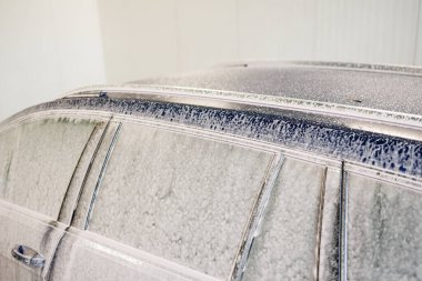 Kirli araba yoğun köpükle kaplı. Otomobil yıkamada mavi araba.