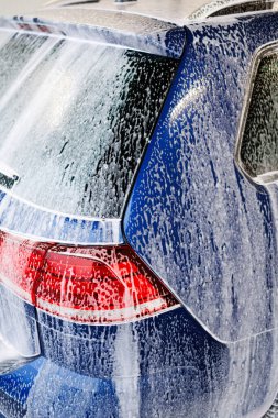 Yakın plan fotoğraf. Kalın köpüklü araba parçaları. Kirli araçları yıkamak için kimyasallar..