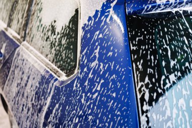 Yakın plan fotoğraf. Kalın köpüklü araba parçaları. Kirli araçları yıkamak için kimyasallar..