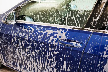 Yakın plan fotoğraf. Kalın köpüklü araba parçaları. Kirli araçları yıkamak için kimyasallar..