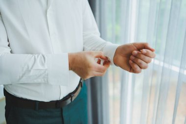 Pırıl pırıl beyaz gömlek giyen bir adam kelepçelerini düzeltiyor. Parlak ve huzurlu bir ortamda güzelce yakalandı.