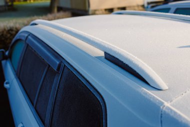 Donmuş bir arabanın çatısını gösteren yakın plan bir görüntü, çeşitli araçlarda kışın hassas dokunuşlarını gösteriyor.