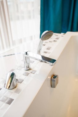 Şık ve modern bir banyo musluğu ve canlı ve canlı bir perde arkası olan duş başlığı.