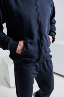 Siyah ceketli ve siyah pantolonlu bir adam ellerini cebine sokup rahat bir hava yaratıyor.