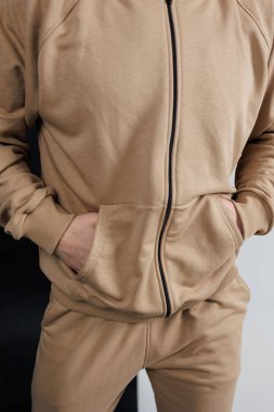 Şık bir ceketle uyumlu pantolonu olan ve ellerini rahatça cebine saklayan bir adam.