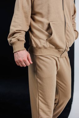 Bir adam bronz kapüşonlu bir kapüşonlu ve ona uygun bir eşofman giyiyor. Günlük kıyafet için rahat ama şık bir kıyafet yapıyor.