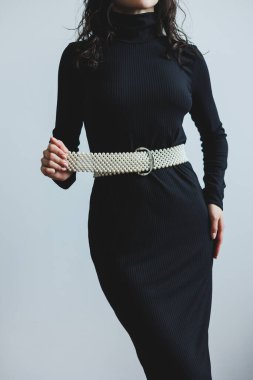 Modern moda fotoğrafçılığı için mükemmel, eşsiz beyaz kemeri olan zarif ve modaya uygun bir siyah elbise.
