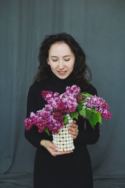 Genç bir kadın, doğal güzellik ve zarafetin özünü yakalayan canlı bir leylak buketine hayran.