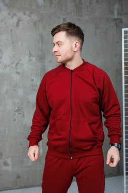 Canlı kırmızı atletik giysiler giymiş kendine güvenen bir adam modern bir ortamda şık ve dinamik bir şekilde poz verir.