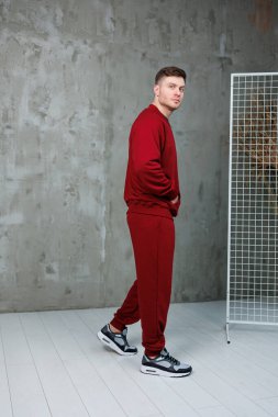 Canlı kırmızı eşofmanlı, modern atletizm stili ve genç enerjisiyle şık bir genç adam.