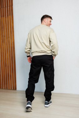 Şık bir adam, spor unsurları ve özellikleriyle vurgulanmış modern bir günlük kıyafet sergiliyor.