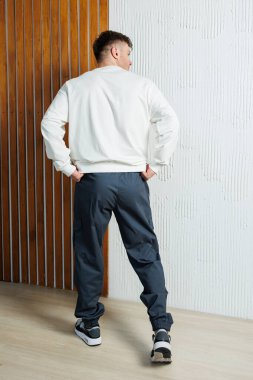 Şık bir erkek model, şık ve modern bir arka plan tasarımına karşı rahat bir kıyafet sergiliyor.