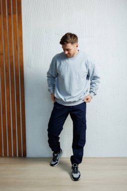 Bir erkek, hem rahatlığı hem de yeteneği mükemmel bir şekilde koordine eden modern bir gündelik stil sergiliyor.