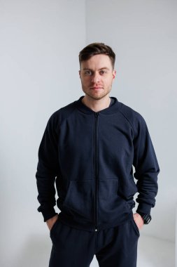 Kendine güvenen genç bir adam modaya uygun ve günlük atletik giysiler içinde modern ve şık bir görünüm sergiliyor.