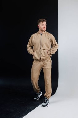 Modaya uygun bej eşofman giymiş şık bir adam çeşitli zıt geçmişlere karşı durabilir.