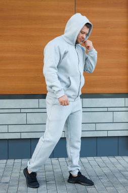 Gri eşofmanlı bir adam. Soğuk yürüyüşler için erkek postu. Erkek modası.