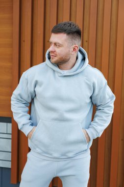 Gri eşofmanlı bir adam. Soğuk yürüyüşler için erkek postu. Erkek modası.