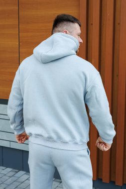 Gri eşofmanlı bir adam. Soğuk yürüyüşler için erkek postu. Erkek modası.