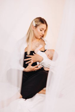 Küçük oğlunu kucaklayan gülümseyen genç bir anne. Mutlu annelik.