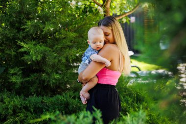 Mutlu anne oğluyla dinleniyor. Mutlu aile yazın parkta dinleniyor. Anne ve oğlu dinleniyor. Genç anne ve onun sevimli küçük çocuğu.