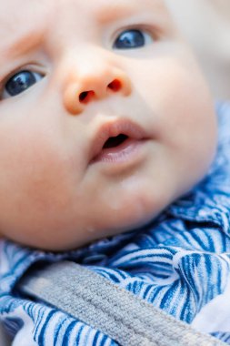 Yazlık gömlekli ve şortlu küçük bir çocuk iskemlede yatıyor. Yeni doğan bebekler için kıyafetler.