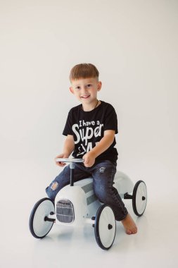 Neşeli bir çocuk renkli bir oyuncak araba sürmekten zevk alır, hem neşeli bir ruh hem de şık bir moda sergiler.