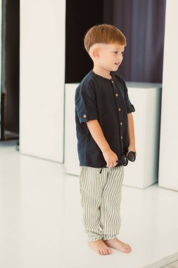 Moda ve şık genç bir çocuk geleneksel bir kıyafet giyer. Modern bir yetenekle harmanlanır, yalınayak durur.