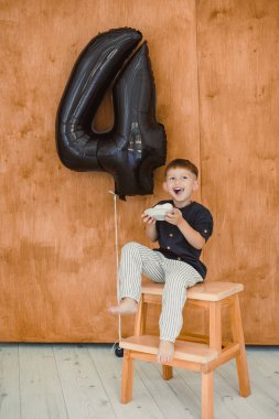 Neşeli bir çocuk dördüncü doğum günlerini yakına yerleştirilmiş 4 numaralı dev bir balonla kutluyor.