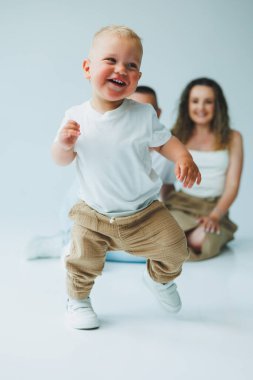 Neşeli bir çocuk neşeli bir şekilde koşuyor ve neşeli, renkli bir alanda oynuyor. Sevgi dolu bir aile yanında.