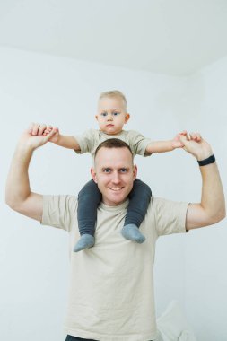 Neşeli bir baba, mutlu bir şekilde küçük çocuğuna omuzlarında eğlenceli bir yolculuk yaşatıyor. Bağlarını ve bağlarını gösteriyor.