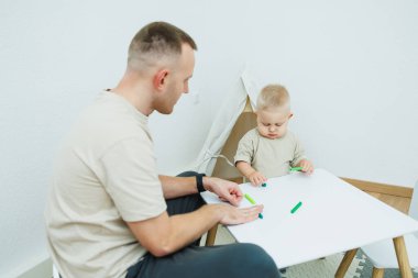 Bir baba ve yeni yürümeye başlayan çocuğu renkli bloklarla yaratıcı oyun zamanı geçirip bağ kurmayı ve gelişmeyi teşvik ediyorlar..