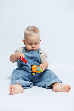 Sevimli küçük bir çocuk neşeli bir şekilde parlak ve renkli bir oyuncak arabayla meşgul oluyor, masumiyetlerini sergiliyor.