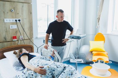 Karı koca doğum odasında bir çocuğun doğumuna hazırlanıyorlar. Koca, doğum sırasında karısına destek oluyor. Kadın kocasının huzurunda doğum yapıyor.