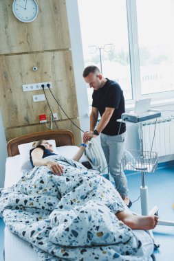 Doğum odasında bir çocuk doğurmaya hazırlanan mutlu aile çifti. Kadın yatakta yatıyor ve bir çocuk doğuruyor. İlgili bir koca, doğum sırasında karısına destek olur..