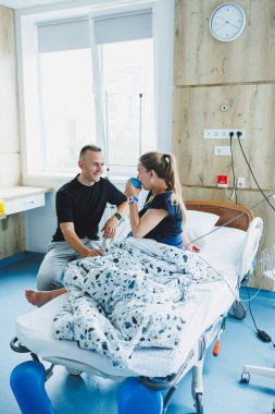 Doğum odasında bir çocuk doğurmaya hazırlanan mutlu aile çifti. Kadın yatakta yatıyor ve bir çocuk doğuruyor. İlgili bir koca, doğum sırasında karısına destek olur..