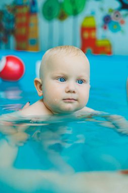 Anne ve bebek havuzda yüzmekten hoşlanırlar. Bebek bir cankurtaranla yüzmeyi öğreniyor..