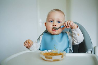 Sevimli bir bebek, kendini beslerken eğlenceli ve dağınık bir karışım sergiliyor.