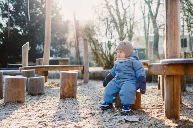 Dışarıda oynayan kışın giydiği tulumlu küçük çocuk. Çocuk kış yürüyüşüne çıkmış..