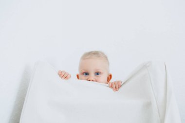 Parlak oturma odasında gülümseyen sarışın çocuk. Küçük çocuk evde oynuyor ve kameraya gülümsüyor..