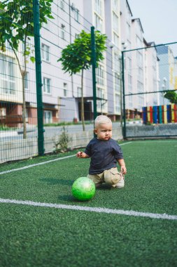 Neşeli bir çocuk, çocukluk ve açık hava eğlencesini gözler önüne seren yumuşak yeşil çimenlerde neşeyle oynar.