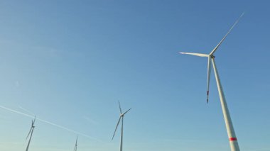 Sahada büyük yel değirmenleri dönüyor ve enerji üretiyor. Eko enerji üretimi. Gökyüzünde yel değirmenleri.