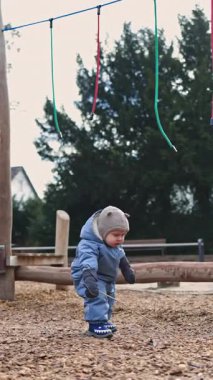 Küçük çocuk parkın parkında parlayan ellerle oyun teçhizatıyla oynuyor. Kışın soğuk havada dışarıda oynayan bir çocuk..