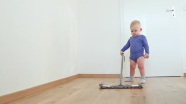 Küçük çocuk bir paspasla yerleri yıkıyor. Çocuk yerleri temizlemeye yardım ediyor. Pamuklu elbiseli bir çocuk..