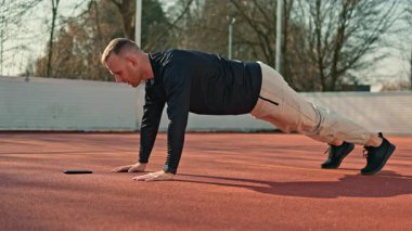 Eşofmanlı ve formalı genç bir adam basketbol sahasında spor yapıyor. Atletik vücutlu bir adam dışarıda spor yapıyor..