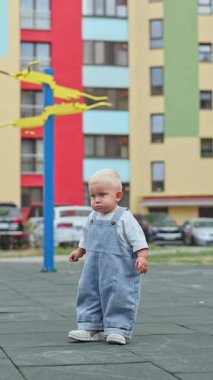 Oyun parkında koşan kot pantolonlu küçük bir çocuk. Küçük çocuk dışarıda oynuyor. Çocuk gelişimi.