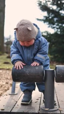 Küçük çocuk 1 yaşında, tulumlu, koşuyor ve dışarıda oynuyor. Çocuk dışarıda koşuyor. çocuk gelişimi.