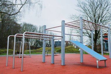 Ortasında rahat bir mavi bankın bulunduğu canlı bir oyun alanı, aileler ve çocuklar için mükemmel, açık hava eğlencesine davet edici.