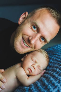 Huzurlu ve sıcak bir ortamda, bir baba, huzur içinde uyuyan bebeğini kucaklayarak, ikisinin arasındaki derin sevgi ve şefkat bağını güzelce gösterir.