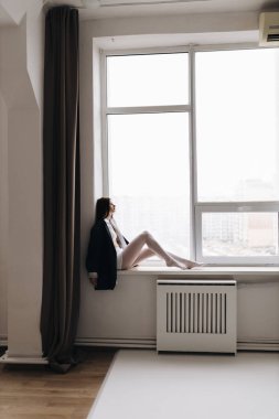 Düşünceli bir kadının sakin ve sakin bir sahnesi. Büyük ve davetkar bir pencerenin düşüncelere daldığı.